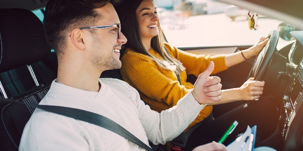 Driving school or test. Beautiful young pregnant woman learning how to drive car together with her instructor.