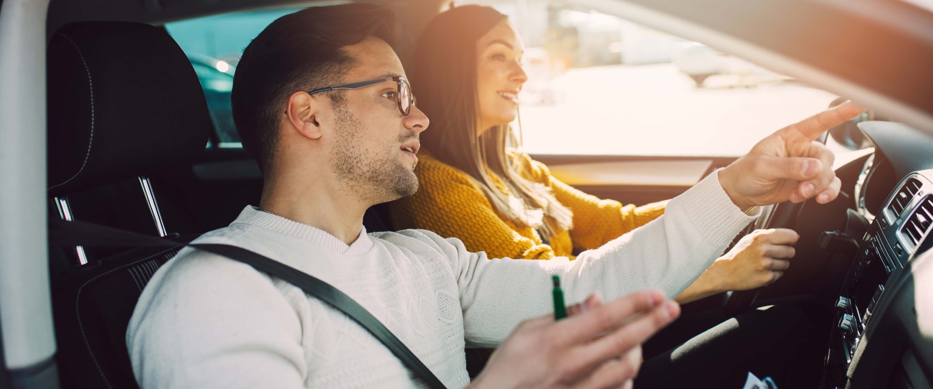 Driving school or test. Beautiful young pregnant woman learning how to drive car together with her instructor.